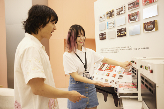 삼성전자가 글로벌 식품 기업 '허쉬'의 초콜릿 포장재 디자인이 적용된 '삼성 프렌즈' 모바일 액세서리 신제품을 2선보였다. 모델들이 허쉬 협업 액세서리를 만나볼 수 있는 '허쉬 플립 투어'에서 사진을 찍고 있다.  삼성전자 제공